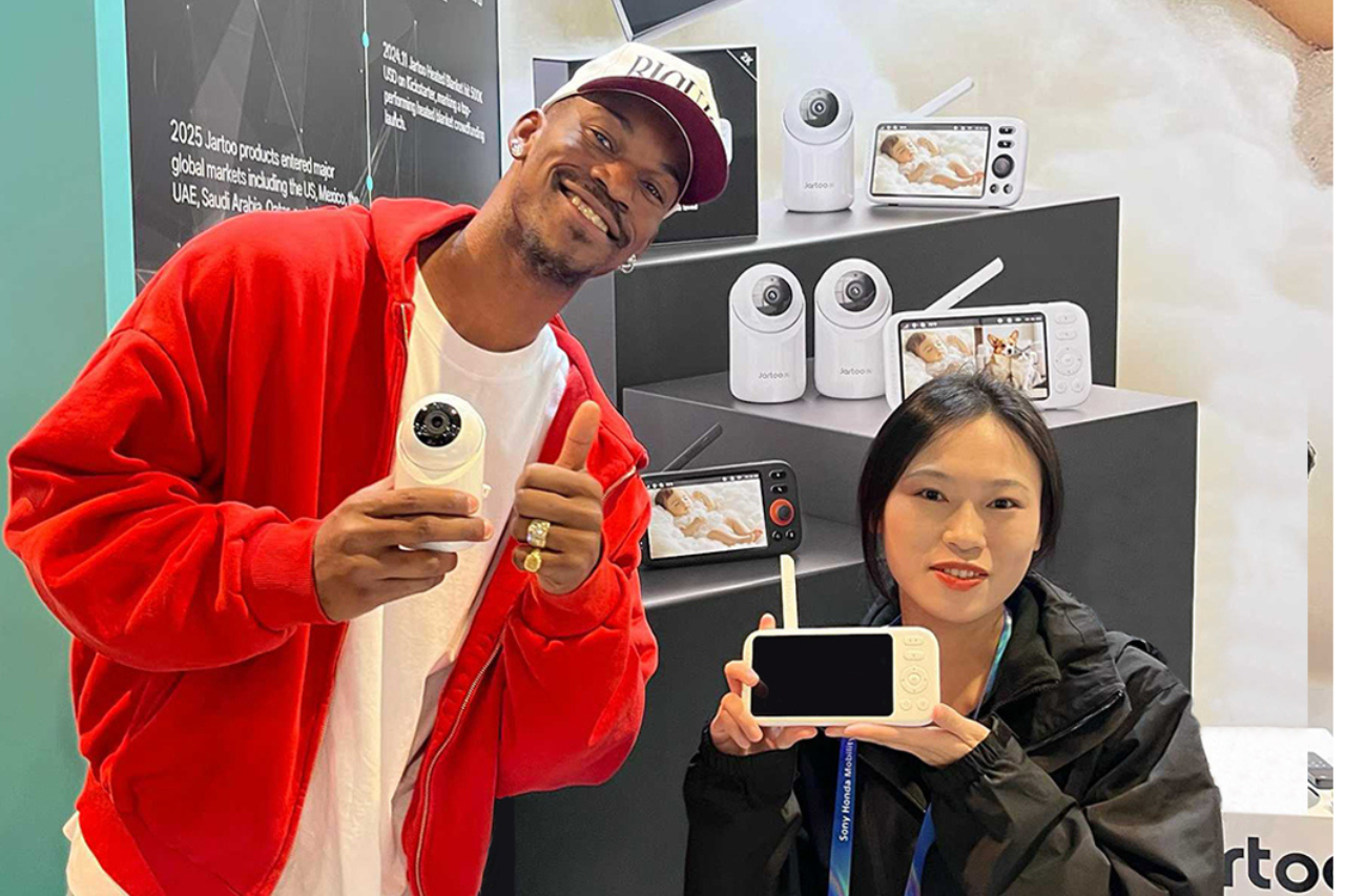 Stay connected at a glance: A hand holds a white baby monitor display, showing a clear, real-time feed of a happy baby playing in their crib. Perfect for instant peace of mind.